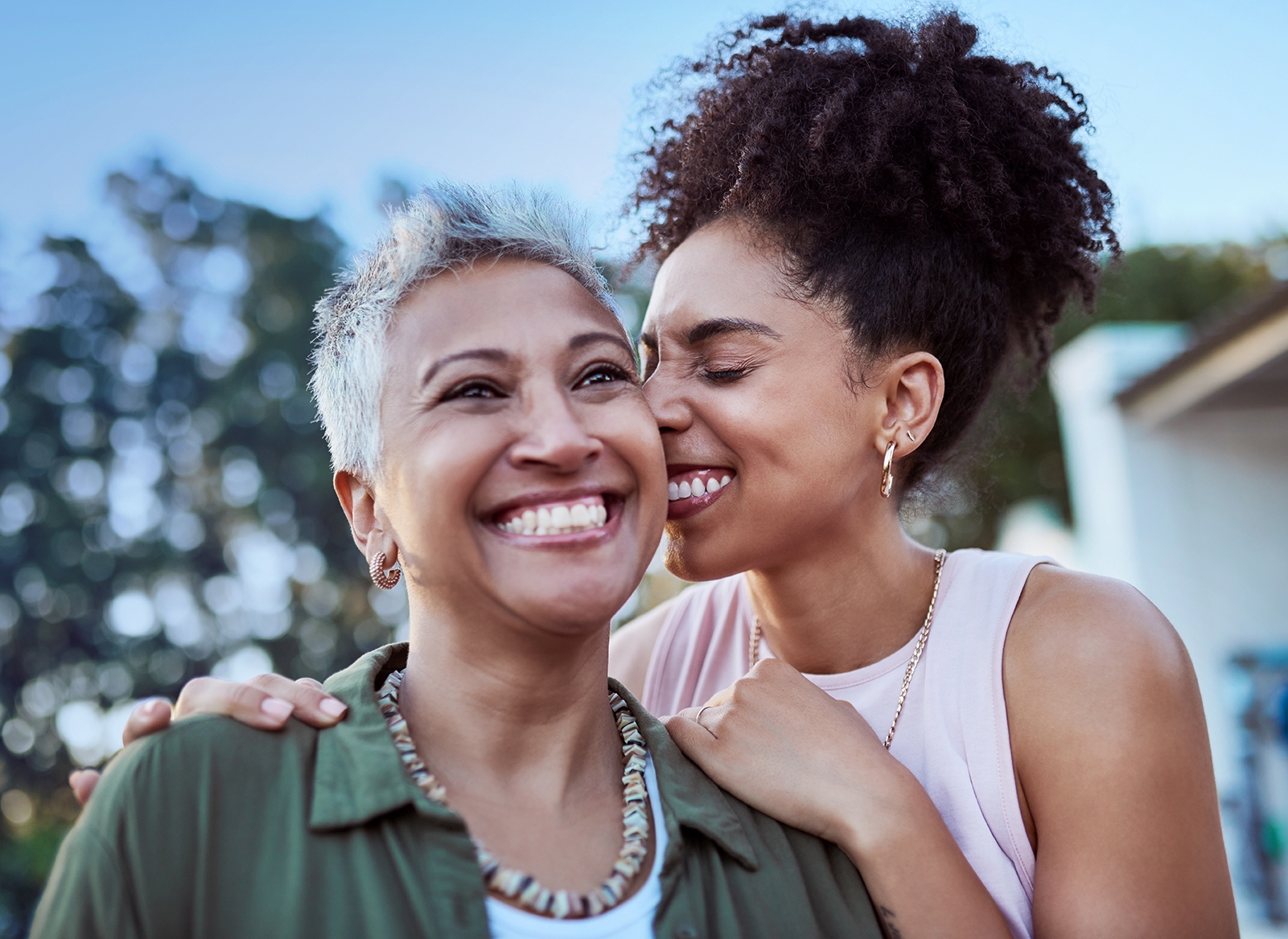 Younger woman hugging older woman, both smiling.