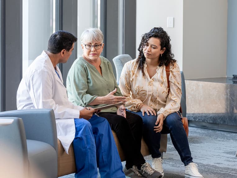 Two women sitting on a couch speaking with a clinician.